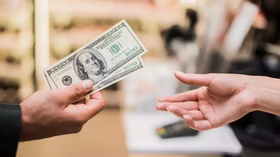 Someone handing cash over to another person