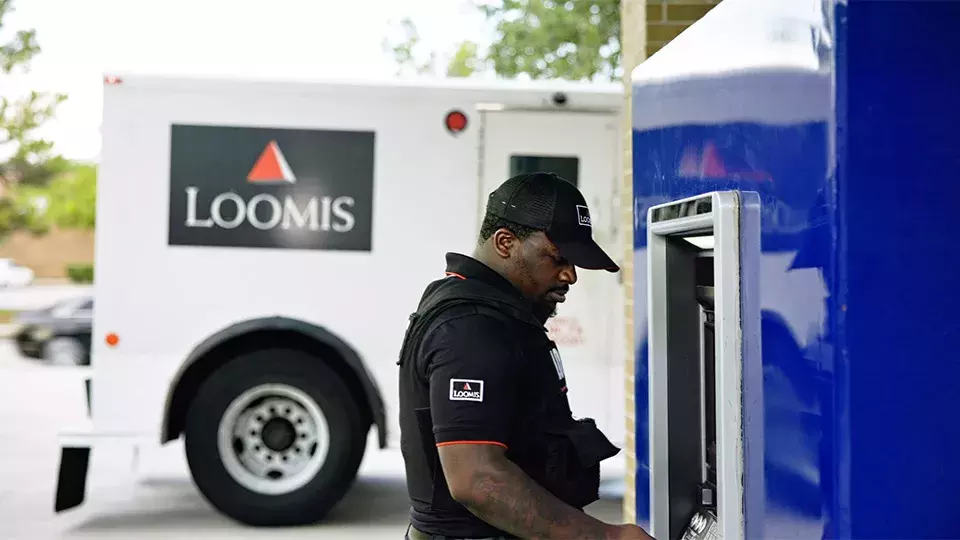 Loomis worker at ATM with Loomis armored car in background