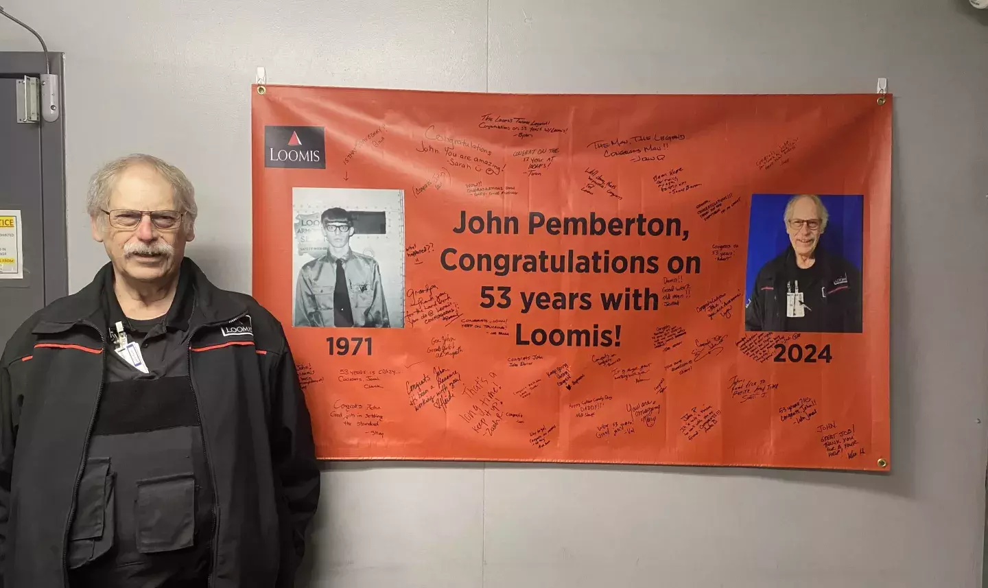 John Pemberton in front of a "congratulations" banner